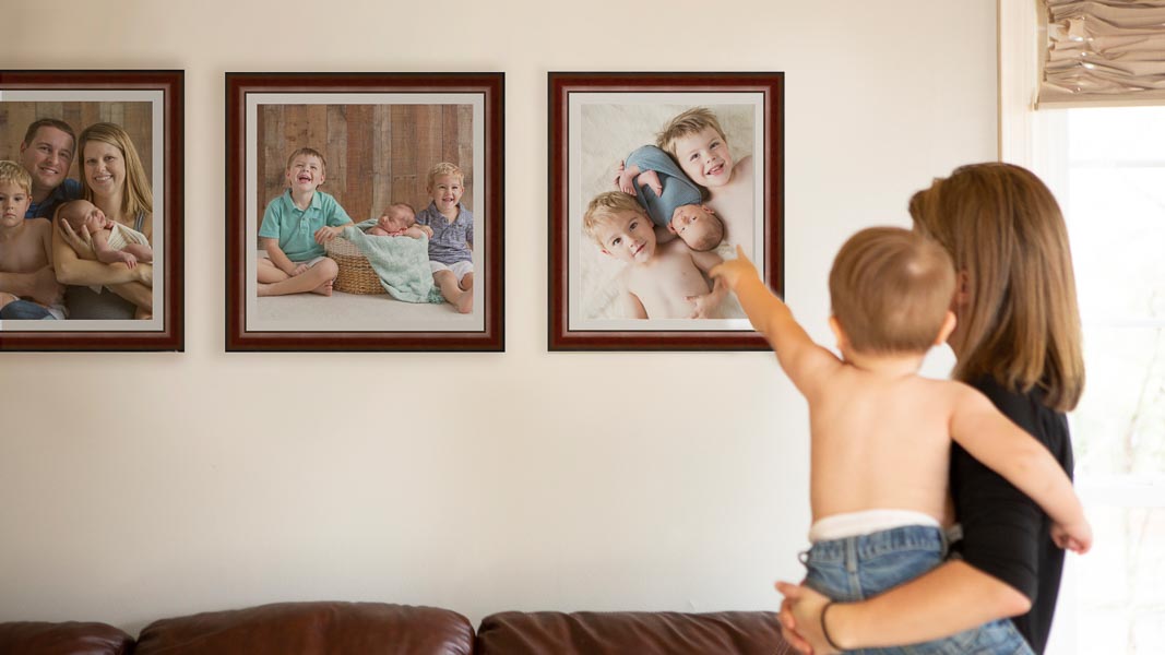 Mom holding baby who is pointing at his picture from his newborn photo session.