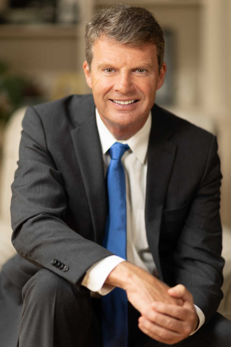 Senior Portrait of a Graduate walking down a road in a red dress and graduation cap.